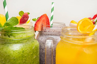 Her biri farklı renklerde meyve püresi içeren bir çemberde dizilmiş bir grup temiz kavanoz. Camların berraklığı sayesinde gökkuşağı etkisi yaratıyor.