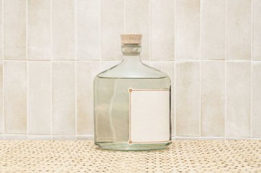 Geometrik şekli ve ahşap tıpası ile kaliteli bir şişe cin ya da votka, koyu renkli bir masanın cilalı yüzeyine, kurutulmuş botaniklerle ya da bir dilim narenciye ile çevrili bir şekilde yansıtılır..