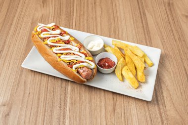 Erimiş çedar peyniri kılıfına sarılı bir sosisli, üzerine pastırma parçaları serpiştirilmiş ve ince doğranmış soğanlar serpiştirilmiş.