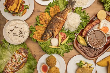 Kalay tabağı ya da içi kızarmış balık filetosu, yeşil muz ve avokado salatası dolu ahşap bir tepsi.