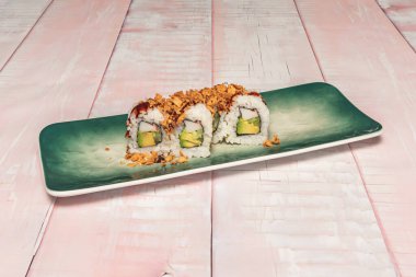 Somon ve avokado uramaki ile bir tabak, ve ton balığı ve soğanlı diğerleri, ters çevrilmiş rulolardaki dolguların çeşitliliğini gösteriyor.