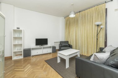 Porselen döşemeden kanepeye kadar gri tonlarda bir oturma odası sadece doğrusal biyoetanol şöminesi, büyük yeşil yapraklar ve bordo kadife yastıklar ile kırılır..