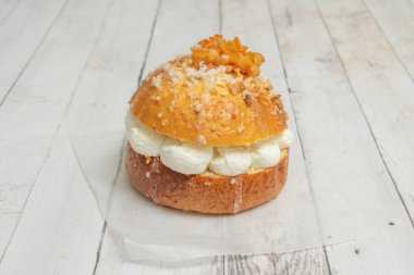 Bir tepside kremalı mini roscn kekleri gösteriliyor, bir tanesi ısırılarak yenmiş, sadece dolguyu değil, aynı zamanda olası ödülü veya sürprizi de ortaya çıkarıyor.