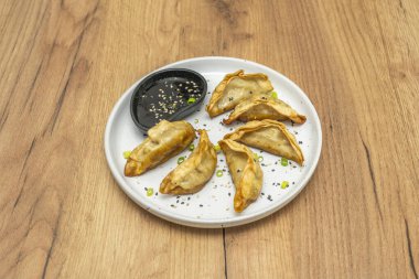 Kızarmış ya da buharda pişirilmiş gyozalar ince hamurun içindeki domuz ve sebzeleri göstererek bir tabakta servis ederler.