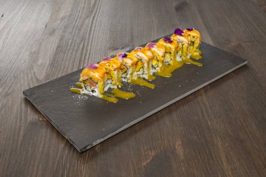 Assorted uramaki rolls presented on a shiso leaf or decorated with thin strips of seaweed for color contrast