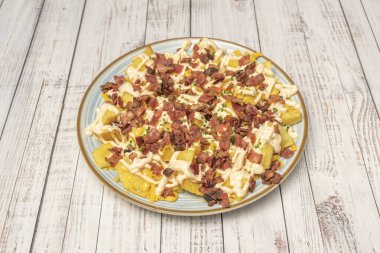 Patates püresinin yumuşaklığı, kızarmış domuz pastırmasının tuzu ve son fırında eritilmiş ve kahverengileşmiş peynirin altın iplikleri arasındaki tezat..