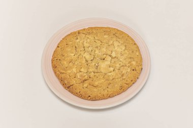 Kalın bir yulaf, tarçın ve kuru üzümlü kurabiyenin yakın çekimi, yulaf gevrekleri ve ışıldayan, sulandırılmış kuru üzümler sıcacık, rahat bir hissi çağrıştırıyor.