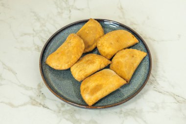 Refakatçilerin ritüeli: sadece empanadaların değil, aynı zamanda salsa criolla, limon ve chimichurri 'nin de yer aldığı, duyusal deneyimi tamamlayan bir sahne.