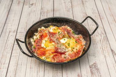 Kalın kesilmiş patatesli bir tabak yumurta, üstünde iki sahanda yumurta, ve birkaç dilim Serrano jambonu, hepsi birbirine karıştırıldığında.