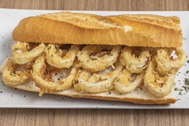 Kızarmış kalamar dolu bir kil tenceresi, sıcak yağdan hala cızırdıyor, masaya yeni getirildi.