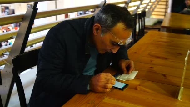 Man holding smartphone studies online sitting in cafe — Stock Video