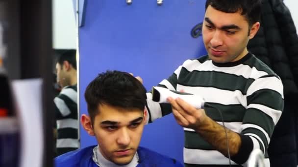 Peluquero acortando el pelo del niño con el cortador eléctrico y tijeras — Vídeos de Stock