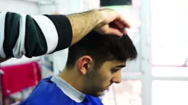 Peluquero acortando el pelo del niño con el cortador eléctrico y tijeras — Vídeos de Stock