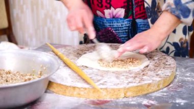 Bir kadın mutfak masasında etli börek hazırlar
