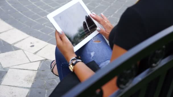 Mladá žena s tabletovým počítačem sedět v městském parku — Stock video