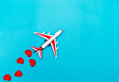 Mavi arka planda uçak oyuncağı ve kalp, aşk yolculuğu konsepti.