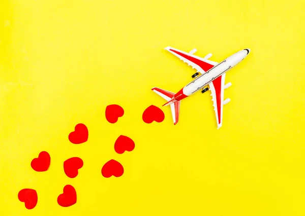Airplane toy and heart on yellow background , love travel concept.