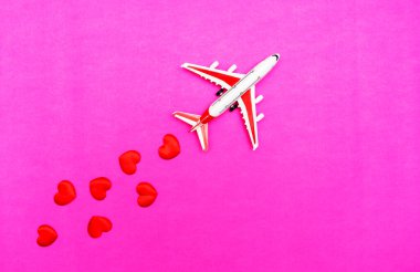 Uçak oyuncağı ve kalbi kırmızı, pembe arka plan, aşk yolculuğu konsepti.