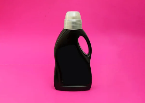 Botol hitam membersihkan bahan kimia pada latar belakang merah muda. — Stok Foto