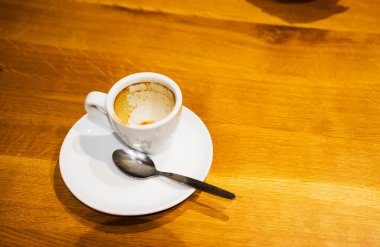 Tahta bir masanın üzerinde kalan espresso lekesini taşıyan beyaz bir fincan.