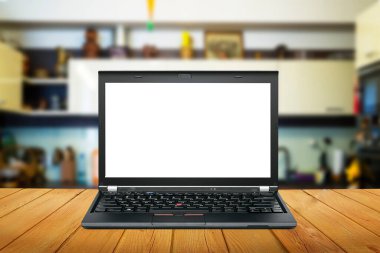 Modern bilgisayar, boş ekranlı dizüstü bilgisayar, ahşap masa ve bulanık mutfak arka planı.