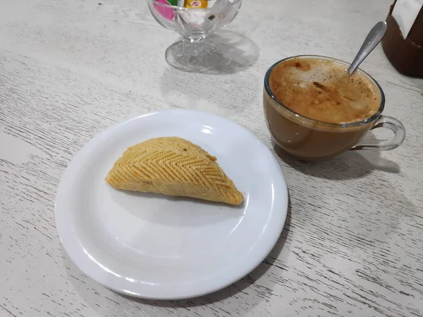 Eine weiße Tasse Kaffee und verschiedene Kuchen auf dem Tisch — Stockfoto