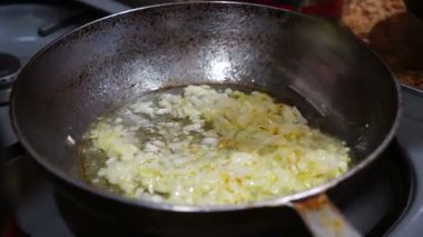 Kadın tavada soğan kızartıyor.