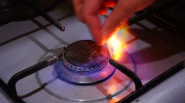 Geleneksel gaz pişirme sobasını yakan bir kibritle kadın eli. ateş