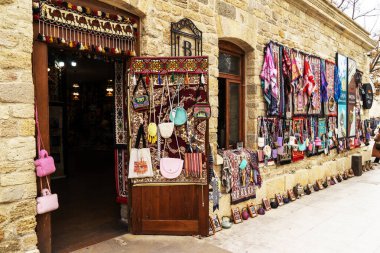 BAKU, AZERBAIJAN - 2 Ocak 2026: Eski Bakü kentindeki Icherisheher 'de alışveriş. Antika halılar, yastıklar, kadın şalları, çantalar, demir ve bakırdan yapılmış el yapımı tabaklar ve çeşitli hediyelik eşyalar indirimde. Eski Bakü şehrinde hediyelik eşyalar. Şey...