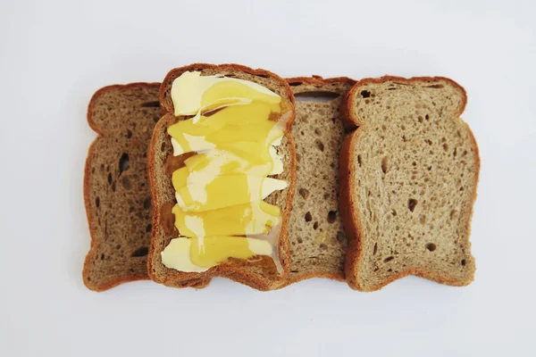 Stukken van zwart brood met boter en honing — Stockfoto