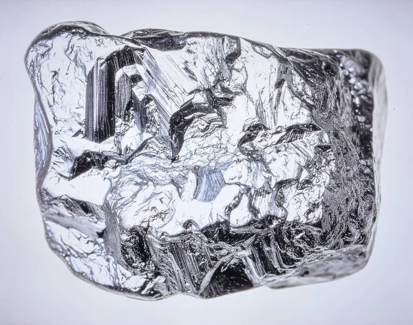 Metalik parlak ve kristal yapıya sahip tek bir ham gümüş cevheri parçası, beyaz arka planda izole edilmiş..