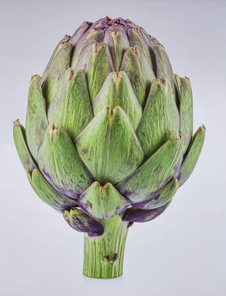 Sıkıca paketlenmiş yeşil yapraklar ve mor uçlu enginar, saf beyaz arka planda izole edilmiş..