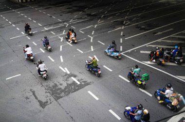 Bangkok, Tayland - 20 Ekim 2024 - Üstgeçidin altındaki çok şeritli kentsel yolda ilerleyen motosikletçiler, yön okları ve şerit ayırıcılarıyla işaretlenmiş.