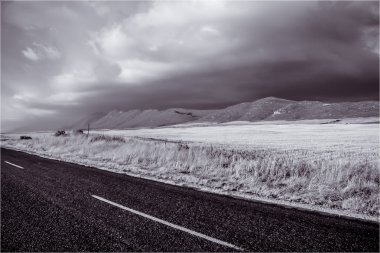 Tarım arazileri ve yol kenarında alınan tepe üzerinde kara bulutlar.