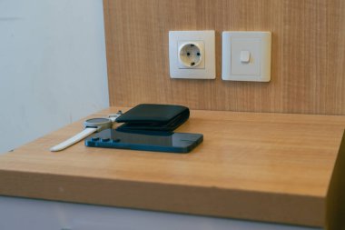 Modern Wooden Desk With Smartwatch Phone And Wallet Near Electrical Outlets