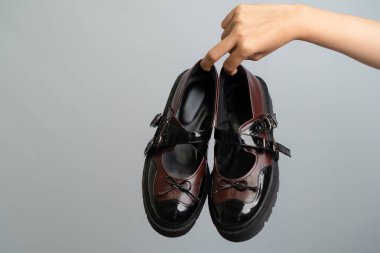 Bir çift kahverengi ve siyah Mary Jane ayakkabıları ile hafif ışıklandırmalı gri bir arka plan