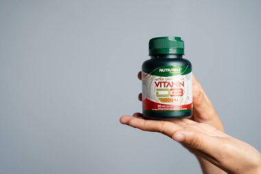 Kemik, Güney Sulawesi, Endonezya, 26 Kasım 2025 - El, Turuncu Kapaklı ve Turuncu Etiketli Temiz Su Şişe Gri Arkaplan Üzerine Metin