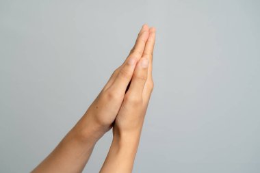 İki insan eli dua ederken birbirine kenetlendi ya da açık gri bir arka plan aydınlatmasına karşı selamlama.