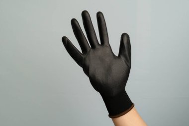 Gri bir arka planda beş parmağı gösteren siyah bir eldiveni kapat