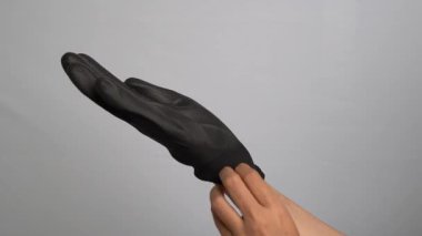 Siyah iş eldivenlerini takan kişi gri arka plana dokunmuş.