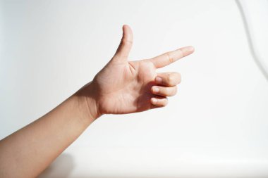 İnsan eli, parmak tabancası yapıyor. Beyaz arka planda hafif ışıklandırmayla hareket ediyor.