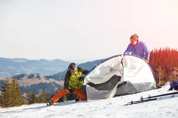Due escursionisti nelle montagne invernali che installano tenda — Foto Stock