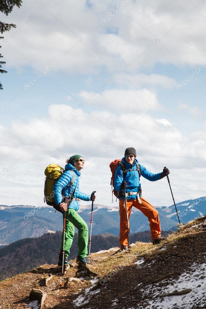Two hikers in winter mountains installing tent