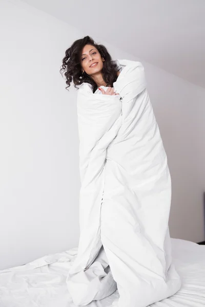 Brunette woman covered by white duvet