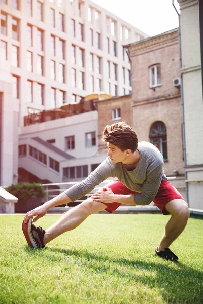 Atleta calentándose y estirándose antes de correr urbano — Foto de Stock