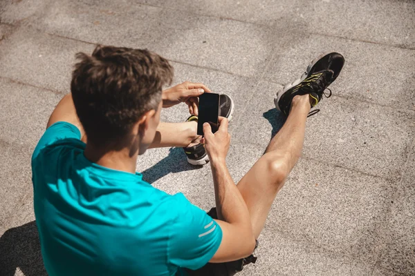 Ugenkendelig mandlig atlet med smartphone - Stock-foto