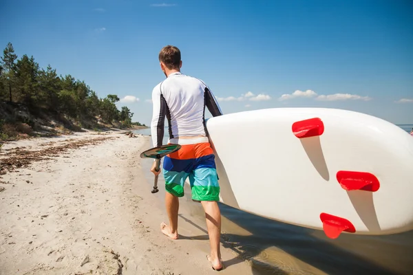 Young man walking out with the sup board — Stock Photo, Image