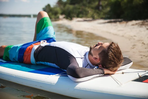 Молодой человек лежит на веслах на пляже — стоковое фото