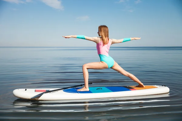 Kürek ile sup tahta üzerinde yoga yaparken kadın