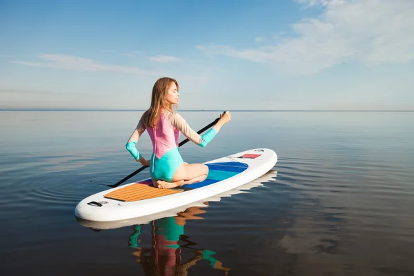 Junge Frau paddelt auf Surfbrett — Stockfoto